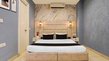 Habitación de hotel con una cama grande, dos mesitas de noche, un equipo de aire acondicionado y una pared con diseño de mármol.
