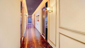 A hotel hallway with a marble floor, wall sconces, and a door with a number. - Townhouse Sector 20 Panchkula (Dera Bassi)