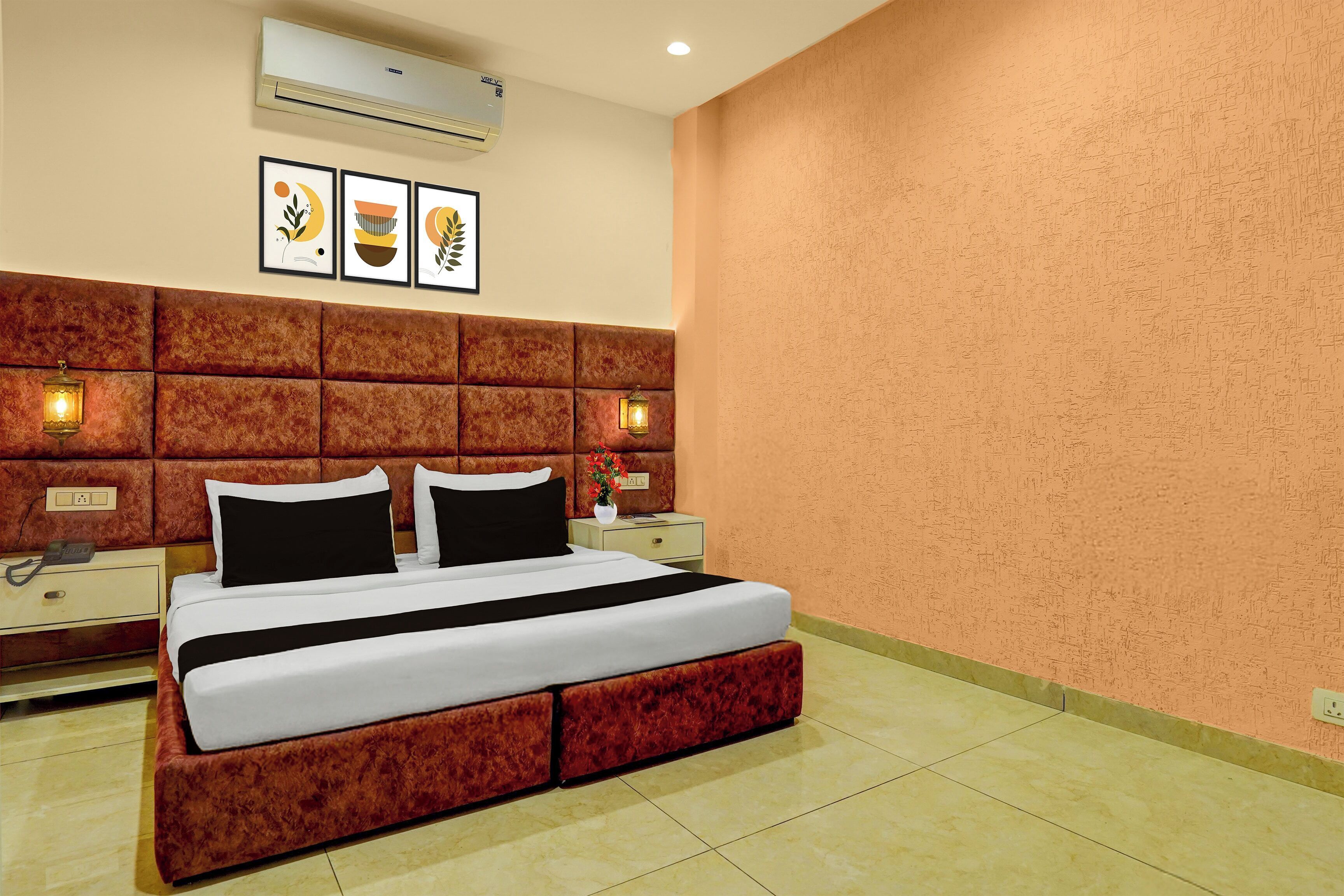 Habitación de hotel con una cama grande, un cabecero acolchado, dos mesitas de noche con lámparas y un aire acondicionado de pared.