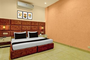 Habitación de hotel con una cama grande, un cabecero acolchado, dos mesitas de noche con lámparas y un aire acondicionado de pared.