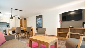 Una sala de estar moderna con sofá, sillas, una mesa de centro y un televisor montado en la pared.