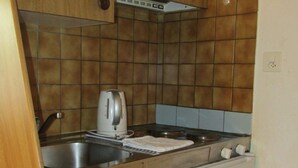 Una cocina compacta con fregadero, estufa y un refrigerador pequeño.
