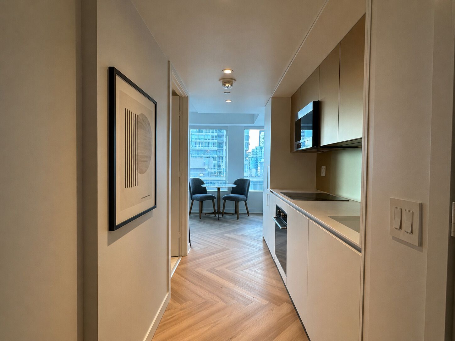A modern kitchen with a dining area, wooden flooring, and a city view.
