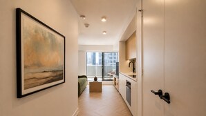 Um corredor com um quadro, um sofá, uma mesa de centro e vista para uma varanda com o horizonte da cidade.