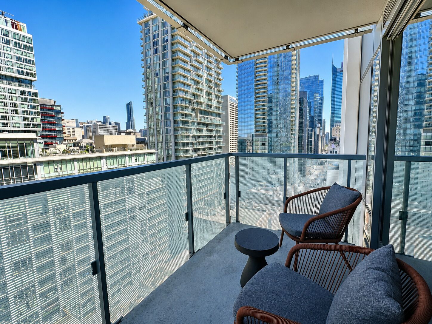 A balcony with wicker furniture and a view of a cityscape.