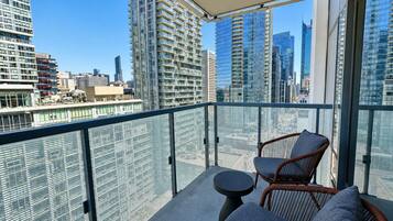 A balcony with wicker furniture and a view of a cityscape.