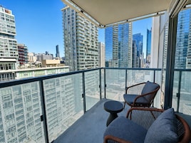 A balcony with wicker furniture and a view of a cityscape.