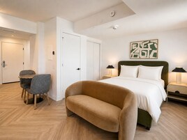 Een hotelkamer met een bed, twee nachtkastjes met lampen, een stoel, een bureau en een deur.