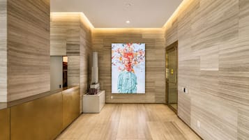 A modern lobby with a reception desk, a digital art display, and a door with a golden handle.