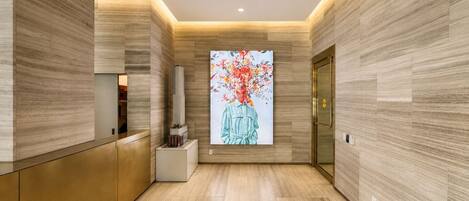 A modern lobby with a reception desk, a digital art display, and a door with a golden handle.