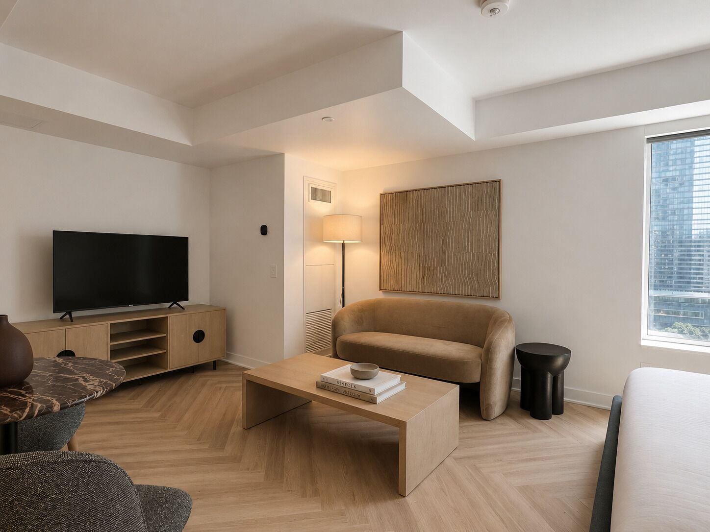 Ett modernt vardagsrum med en platt-TV, en soffa, ett soffbord och en lampa.