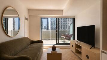 A modern living room with a sofa, a television, and a balcony with a view of the city.
