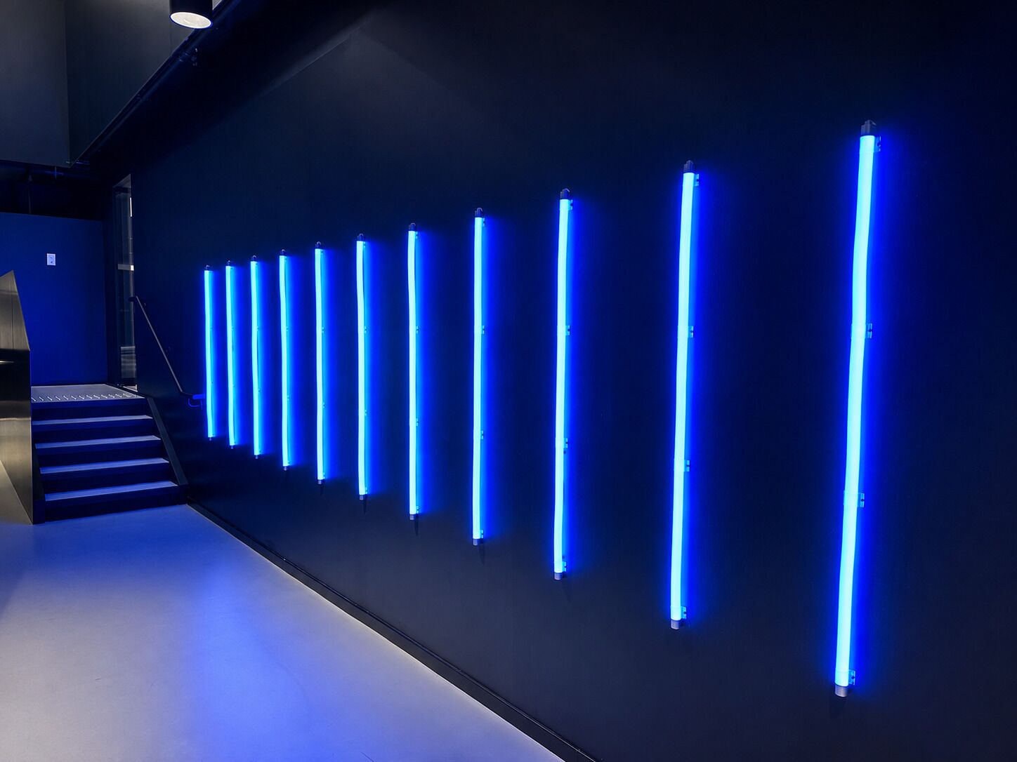 A modern interior with a series of vertical light fixtures on a wall.