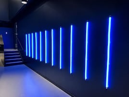 Een modern interieur met een reeks verticale verlichtingsarmaturen aan een muur.