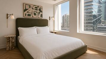 A modern bedroom with a large bed, a city view, and a minimalist design.