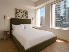 Un dormitorio moderno con una cama grande, vistas a la ciudad y un diseño minimalista.