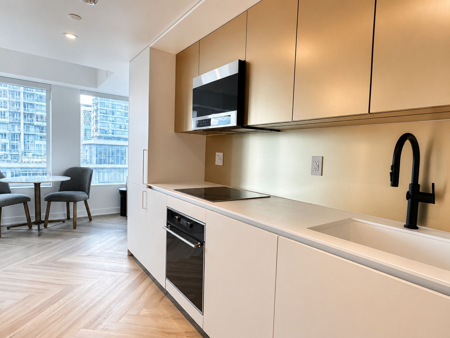 A modern kitchen with a built-in microwave, oven, and a black faucet.