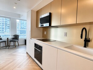 A modern kitchen with a built-in microwave, oven, and a black faucet. - Nester Finn Downtown Toronto (Toronto)