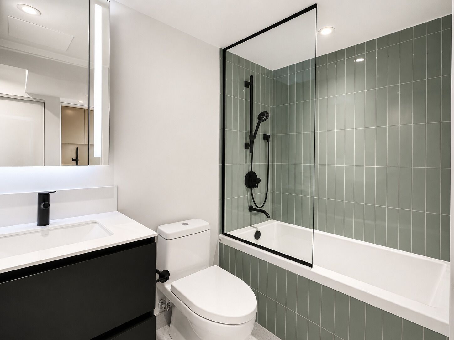 A modern bathroom with a white sink, black cabinet, white toilet, and a glass-enclosed shower area.