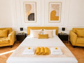 Ein Hotelzimmer mit einem großen Bett, zwei Nachttischen, einem Sofa und Kunstwerken an den Wänden.