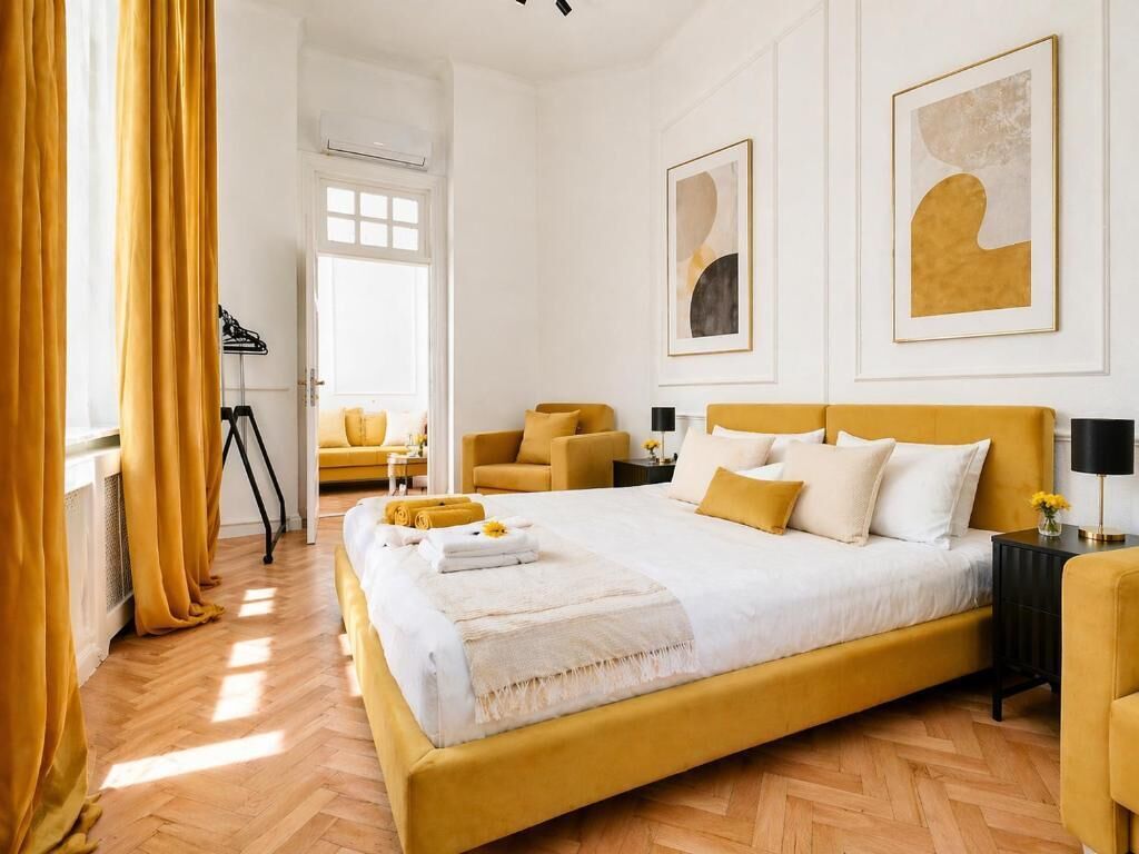 A hotel room with a large bed, a sitting area with a chair, and artwork on the walls.