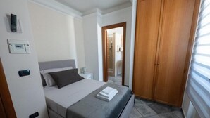 A bedroom with a bed, bedside table, and a wardrobe.