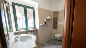 A bathroom with a sink, toilet, and window.