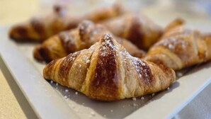 A plate with croissants and a blurred background with bottles.