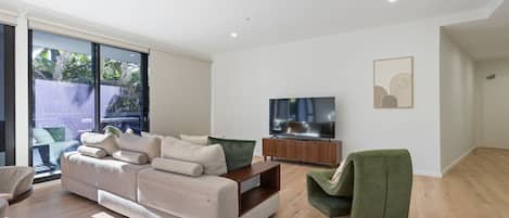 A modern living room with a sofa, a television, and a green armchair.