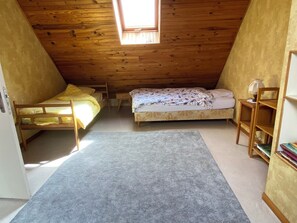 Ein kleines Schlafzimmer im Dachgeschoss mit zwei Etagenbetten, einem Dachfenster, einem Bücherregal und Teppichboden.