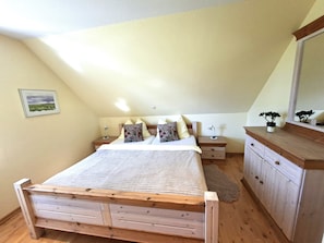 A bedroom with a wooden bed, two bedside tables, a nightstand, a dresser, and a mirror. - Luxury "Lachmöwe" Vacation Rental in Haus Wattenblick (Warwerort)