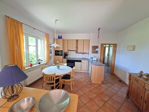 A compact kitchen with a dining area, wooden cabinets, a microwave, and a sink. - High-quality "Strandläufer" vacation rental in Haus Wattenblick with its own sauna (Warwerort)