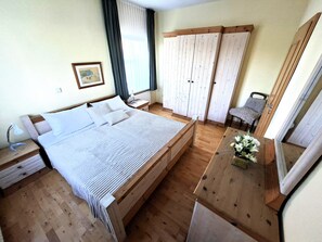 A bedroom with a large bed, wooden flooring, a nightstand, a dresser, a chair, and a wardrobe. - A Comfortable Vacation: The High-Quality "Austernfischer" Vacation Rental in Warwerort (Warwerort)