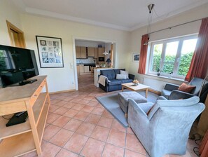 Ein Wohnzimmer mit Fernseher, Sofa und Essbereich.
