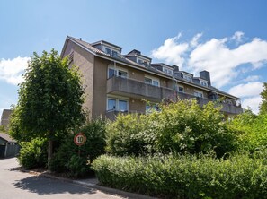 A multi-story residential building with a brick facade, multiple balconies, and a speed limit sign of 10. - A Charming Getaway by the Sea—Cozy Apartment in a Central Beachfront Location in Büsum (Büsum)