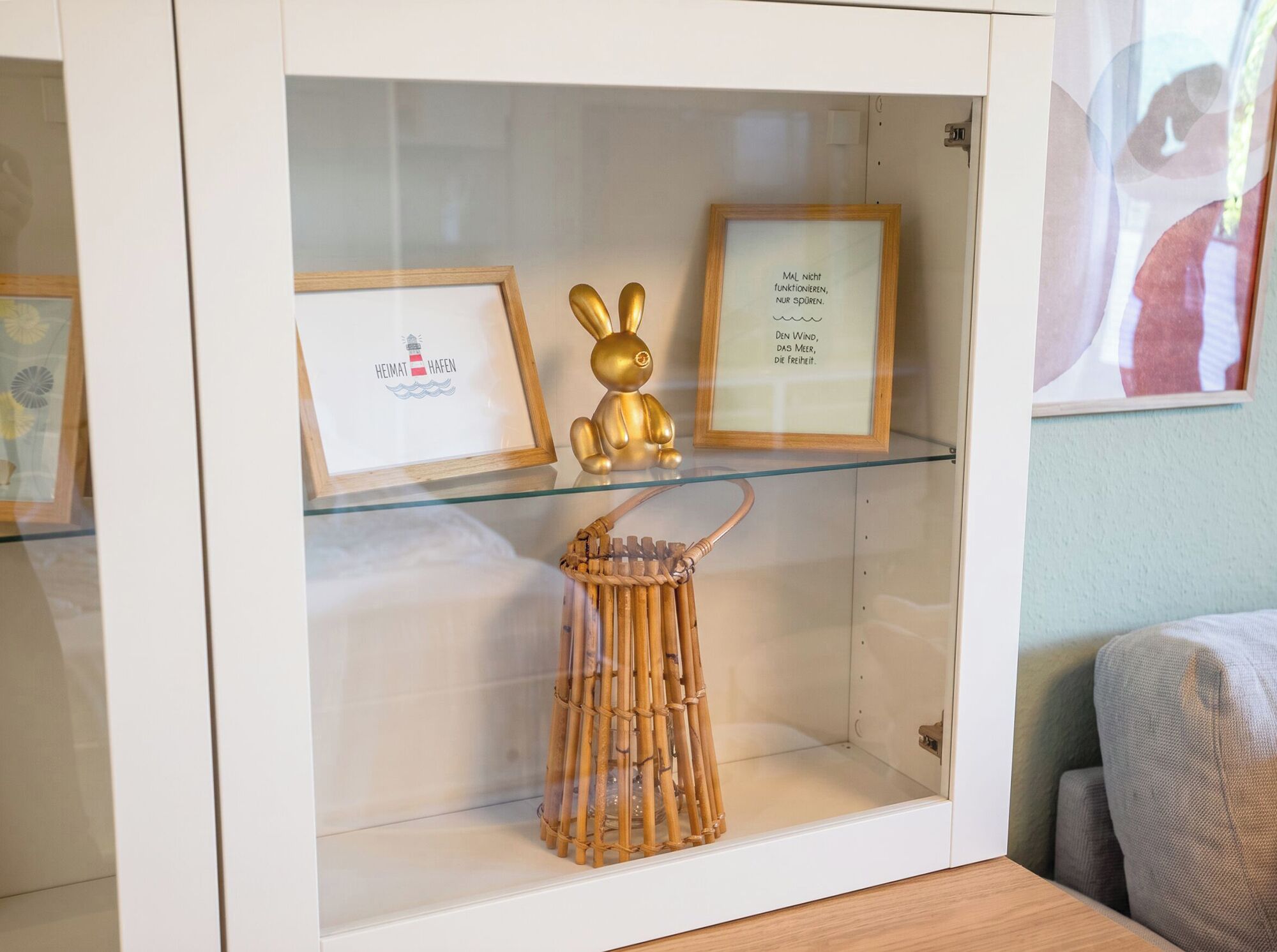 A glass display cabinet with framed artwork and a golden rabbit figurine.