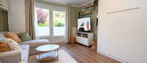 A modern living room with a sofa, a coffee table, a TV, and a white wardrobe.