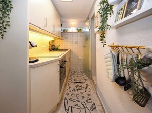 A narrow kitchen with white cabinets, a tiled backsplash, and a black and white patterned rug. - A Charming Getaway by the Sea—Cozy Apartment in a Central Beachfront Location in Büsum (Büsum)