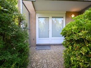 A house entrance with a door, a small porch, and a gravel pathway. - A Charming Getaway by the Sea—Cozy Apartment in a Central Beachfront Location in Büsum (Büsum)