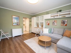 A modern living room with a grey sofa, a wooden coffee table, and a white radiator. - A Charming Getaway by the Sea—Cozy Apartment in a Central Beachfront Location in Büsum (Büsum)