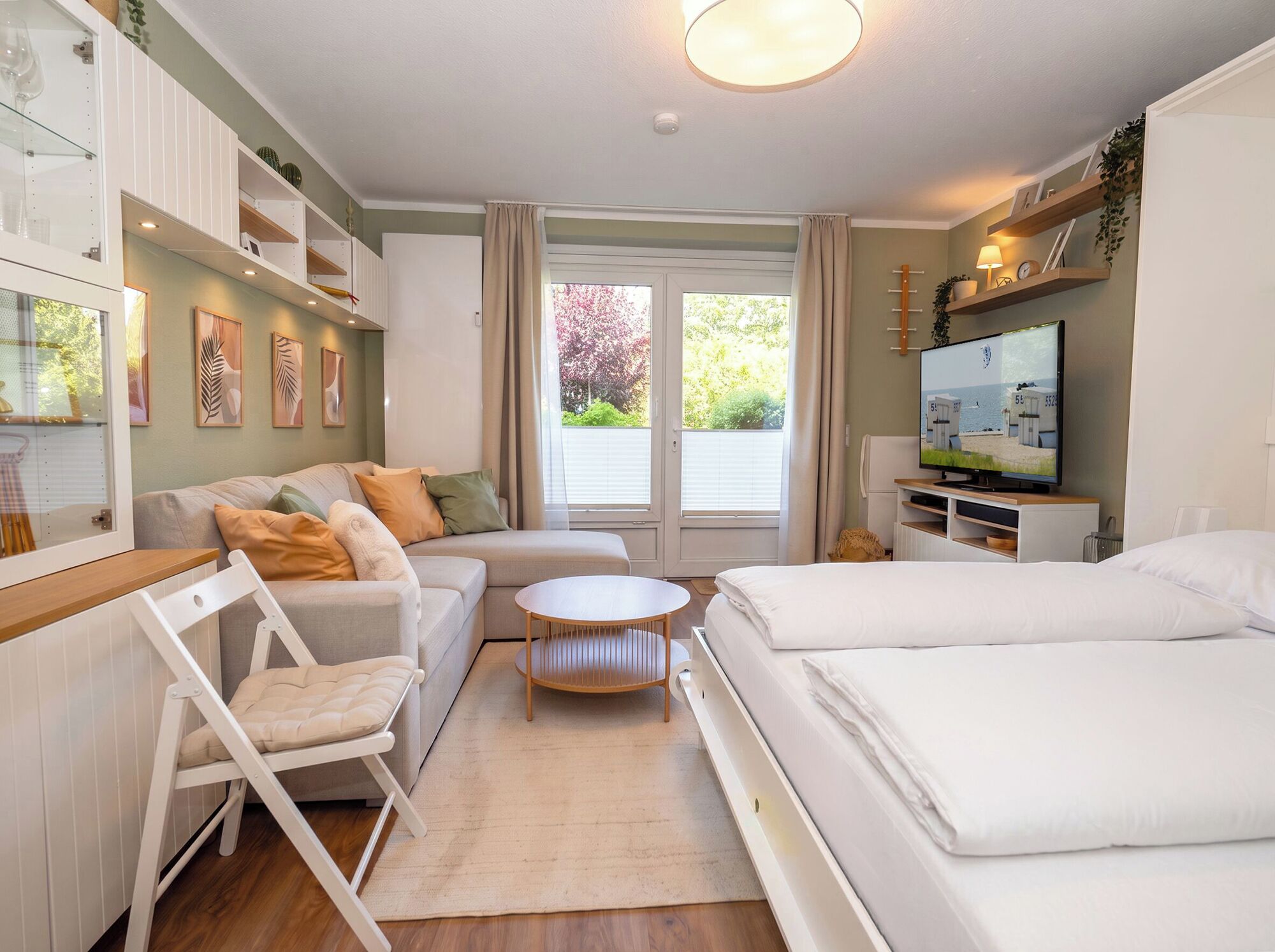 A modern bedroom with a sofa, a small round table, a bed, and a television.
