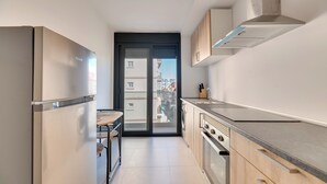 A modern kitchen with a built-in oven, a sink, and a window overlooking a residential area. - LXR Lombok 2-Bedroom by the Sea (Fuengirola)