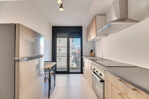 Eine moderne Küche mit eingebautem Ofen, einem Spülbecken und einem Fenster mit Blick auf eine Wohngegend.