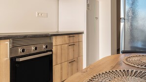 A modern kitchen with a built-in oven, wooden cabinets, and a window with a view. - LXR Lombok 2-Bedroom by the Sea (Fuengirola)