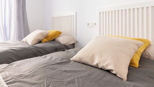 A hotel room with two beds, each with grey bedding and yellow pillows. - LXR Lombok 2-Bedroom by the Sea (Fuengirola)