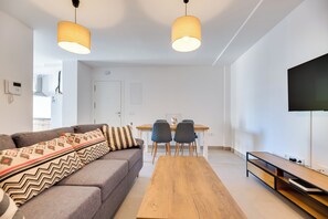 Ein modernes Wohnzimmer mit einer Couch, einem Holztisch und einem Essbereich mit Stühlen.