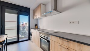 A modern kitchen with a built-in oven, a stainless steel sink, and wooden cabinetry. - LXR Lombok 2-Bedroom by the Sea (Fuengirola)