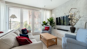 Un salon moderne comprenant un canapé, un fauteuil, une table basse et un téléviseur.