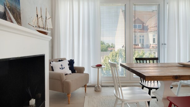 A living room with a fireplace, sofa, and dining table. - Taras na fali AltumStay (Sopot)