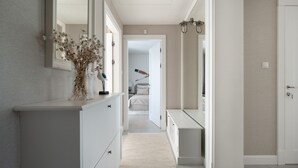Un couloir avec un miroir, une commode et un lit au fond.